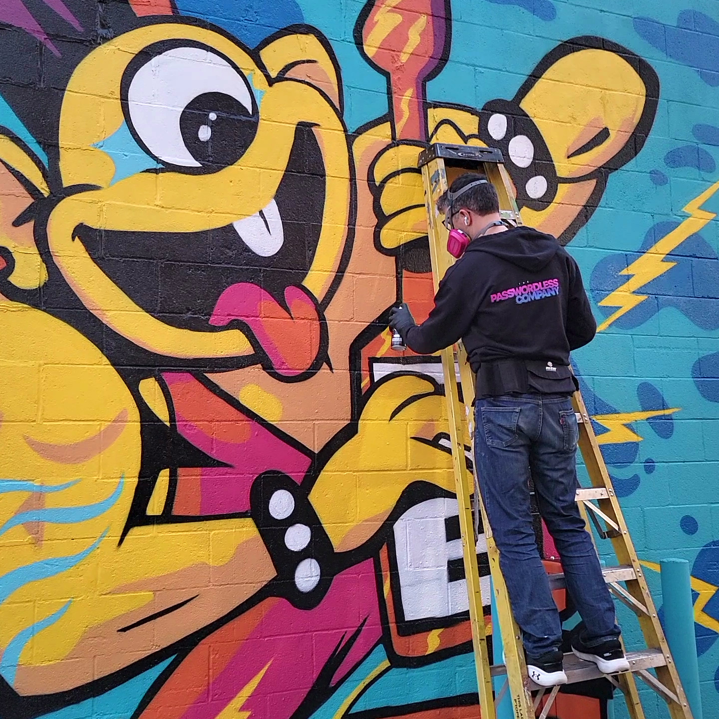 Ross Hardy painting a mural on a wall.